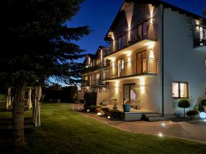 a large white building with lights on it at night at Willa Alexandria - Basen, Cisza, Komfort - Domki i Apartamenty Karwia in Karwia