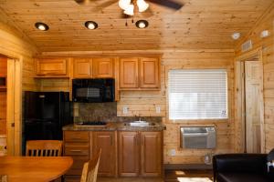 a kitchen with wooden cabinets and a table in a cabin at Ponderosa Camping Resort One-Bedroom Cabin 4 in Lotus