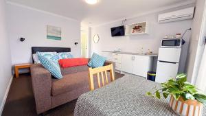 a living room with a couch and a kitchen at Mandurah Coastal Studio - Pool Outlook in Mandurah