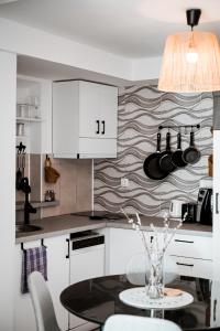 a kitchen with white cabinets and a glass table at Nexus Apartman in Apatin +7 photos