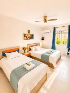 two beds in a room with blue curtains at Pointe D'Esny Villa 1 in Mahébourg