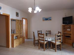 a dining room with a table and chairs and a television at Azúr Vendégház in Hajdúszoboszló