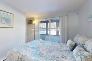 a white bedroom with a bed and a window at Unit 117 for Poolside Fun in Wells
