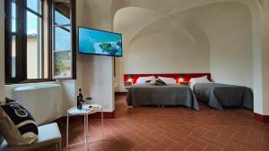 a bedroom with two beds and a flat screen tv at Chiostro Delle Monache Hostel Volterra in Volterra
