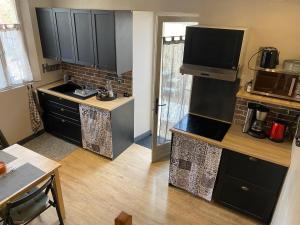 a kitchen with black cabinets and a flat screen tv at Gite L'Atelier in Bèze +4 photos