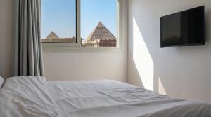 a bedroom with a bed and a tv and a window at King Badr Pyramids Inn in Cairo