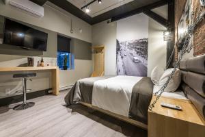 a room with a bed and a desk and a tv at La Suite Hotel in Shawinigan