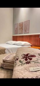 two beds in a room with paintings on the wall at Pousada Bella in Vitória da Conquista