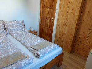 a bed in a room with wooden walls at Azúr Vendégház in Hajdúszoboszló