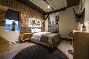 a bedroom with a bed and a brick wall at La Suite Hotel in Shawinigan