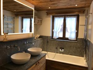 a bathroom with two sinks and a tub and a mirror at Genuss in den Bergen! in Klosters Serneus