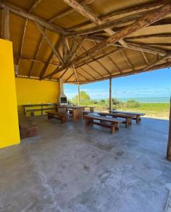 a large pavilion with wooden picnic tables in a field at Pousada Aldeia Do Mar - Caraíva BA in Caraíva