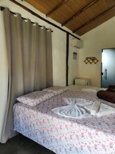 a bedroom with two beds and a curtain at Pousada Aldeia Do Mar - Caraíva BA in Caraíva