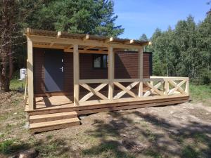 a wooden cabin with a porch and a fence at Powrót do Natury in Orzyny