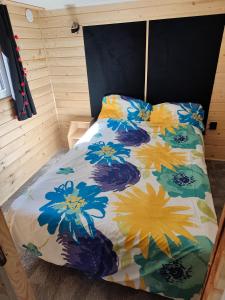 a bed with a colorful comforter in a room at Powrót do Natury in Orzyny
