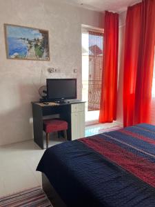 a bedroom with a desk with a computer and red curtains at Helga Apartment in Obzor
