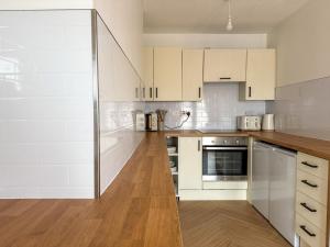 a kitchen with white cabinets and a wooden floor at Spacious Central Flat with Parking in Bangor