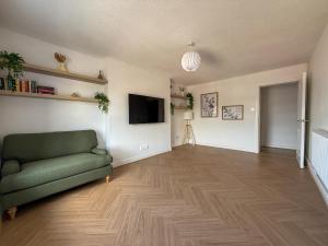 a living room with a green couch and a flat screen tv at Spacious Central Flat with Parking in Bangor