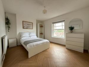a white bedroom with a bed and a window at Spacious Central Flat with Parking in Bangor
