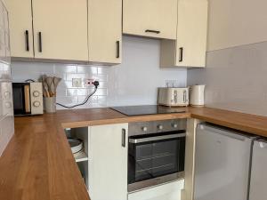 a kitchen with white cabinets and stainless steel appliances at Spacious Central Flat with Parking in Bangor +5 photos