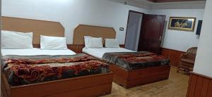 a hotel room with two beds and a chair at hotel ruby international in Kodaikānāl