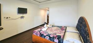 a room with a bed and a tv on the wall at hotel ruby international in Kodaikānāl