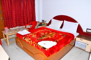 a bedroom with a large bed with a red blanket at hotel ruby international in Kodaikānāl +5 photos