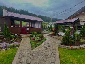 a garden with a stone walkway in front of a house at Карпатський затишок in Verkhovyna