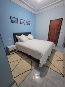 a bedroom with a white bed with a blue wall at Villa RAHA villa entière in El Aggada