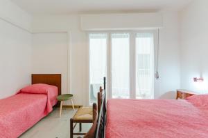 a white bedroom with two beds and a window at Anna Flat - 2 minuti dalla spiaggia in Lido di Jesolo