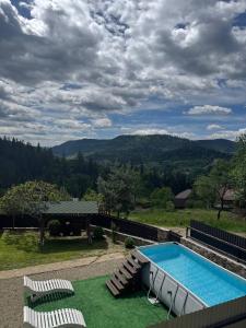 a pool with chairs and a view of the mountains at Hirska Vatra in Slavske