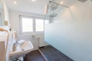 a white bathroom with a sink and a toilet at Hotel Hecht Garni in Ingolstadt