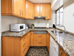 a kitchen with wooden cabinets and a sink and a microwave at CASA EN EL CENTRO HISTORICO in Nerja