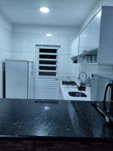 a white kitchen with a sink and a refrigerator at Casa de praia in Marechal Deodoro +1 photo