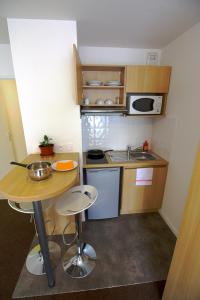 a small kitchen with a table and a microwave at Kosy Appart Hôtel Résidence Arboréa in Heillecourt