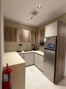 a kitchen with wooden cabinets and a stainless steel refrigerator at ايا ان AYA Inn in Jeddah