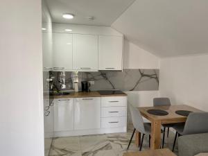 a kitchen with white cabinets and a wooden table at Apartman Žepče in Žepče