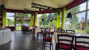 a dining room with tables and chairs and windows at Holländer Mühle Rheinsberg in Rheinsberg