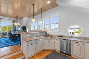 a kitchen with white cabinets and a dining room with a table at Elegant Beachfront Escape with Wrap-Around Porches in Pawleys Island
