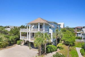 a large blue house with a porch and trees at Elegant Beachfront Escape with Wrap-Around Porches in Pawleys Island