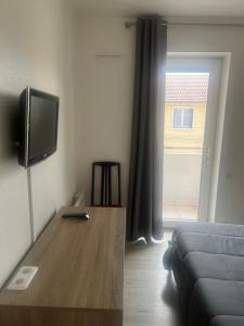 a living room with a tv and a table with a couch at Hôtel Au Bon coin chez Pierre in Franconville
