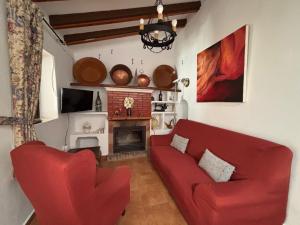 a living room with a red couch and a fireplace at Casa Rural El Castillo in Málaga