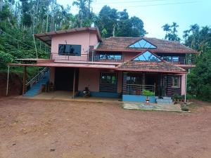 a pink house with a porch and a balcony at Kaarmugilu Homestay in Kalasa
