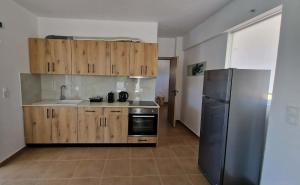 a kitchen with wooden cabinets and a stainless steel refrigerator at Aelia House Kefalos - Cozy & Quiet in Kos