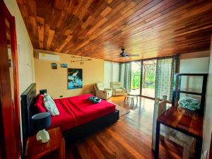 a bedroom with a red bed and a wooden ceiling at Corcovado Nature Homes-Villas-Pool-Jacuzzi-Great Views in Puerto Jiménez +163 photos