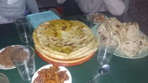 a table topped with a pizza and plates of food at Taddart n Dades in Boumalne Dades