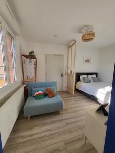 a bedroom with a blue chair and a bed at Les couleurs de Schiltigheim - Aux portes de Strasbourg - Parlement in Schiltigheim