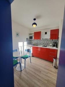 a kitchen with red cabinets and a table and chairs at Les couleurs de Schiltigheim - Aux portes de Strasbourg - Parlement in Schiltigheim