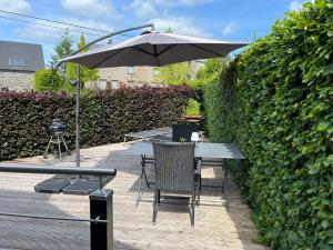 a table and chairs under an umbrella next to a hedge at Gîte Libre’Air in Redu