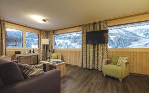 a living room with a couch and a chair and windows at Hotel Landhaus in Münster